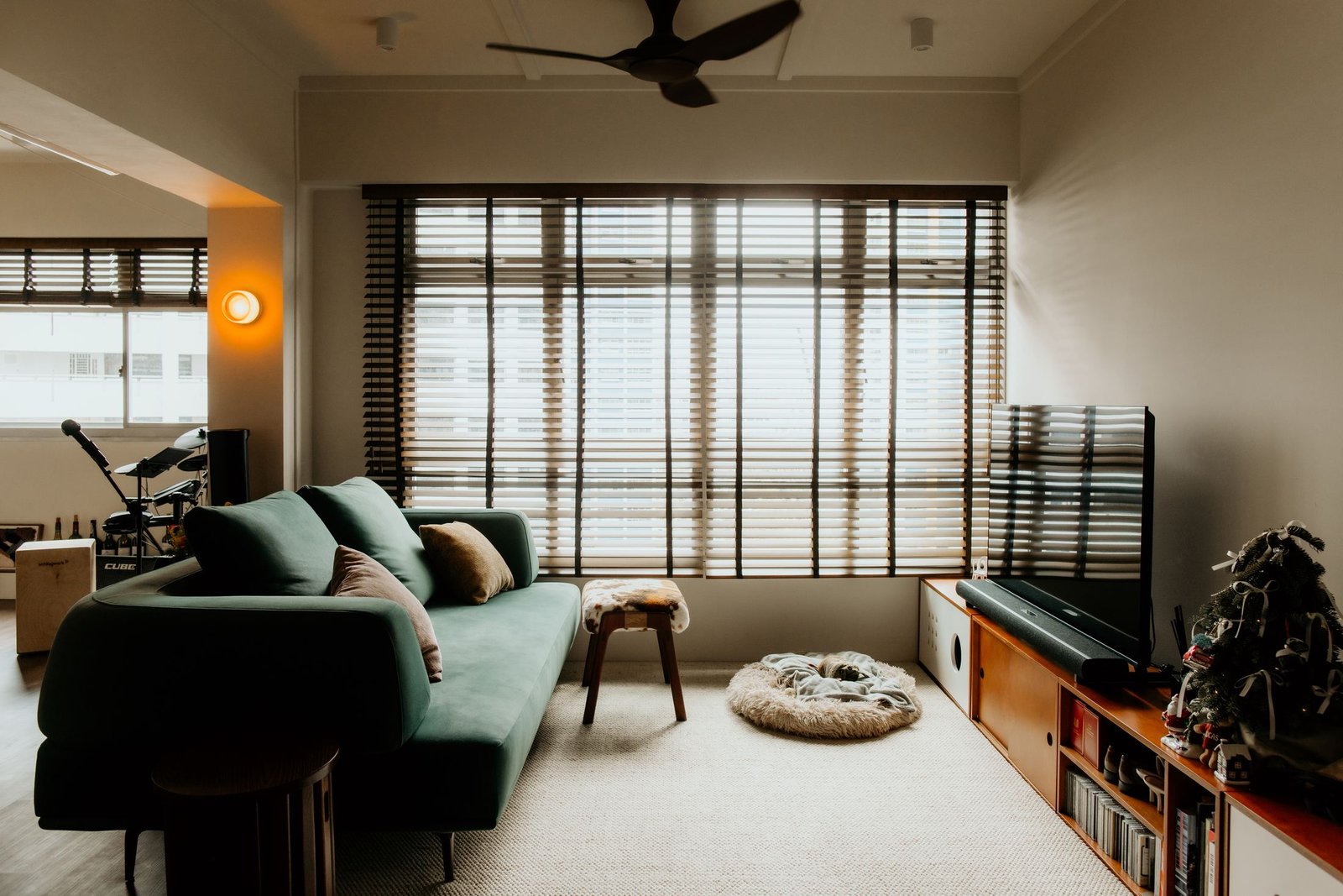 Moody living room with green velvet sofa and venetian blinds