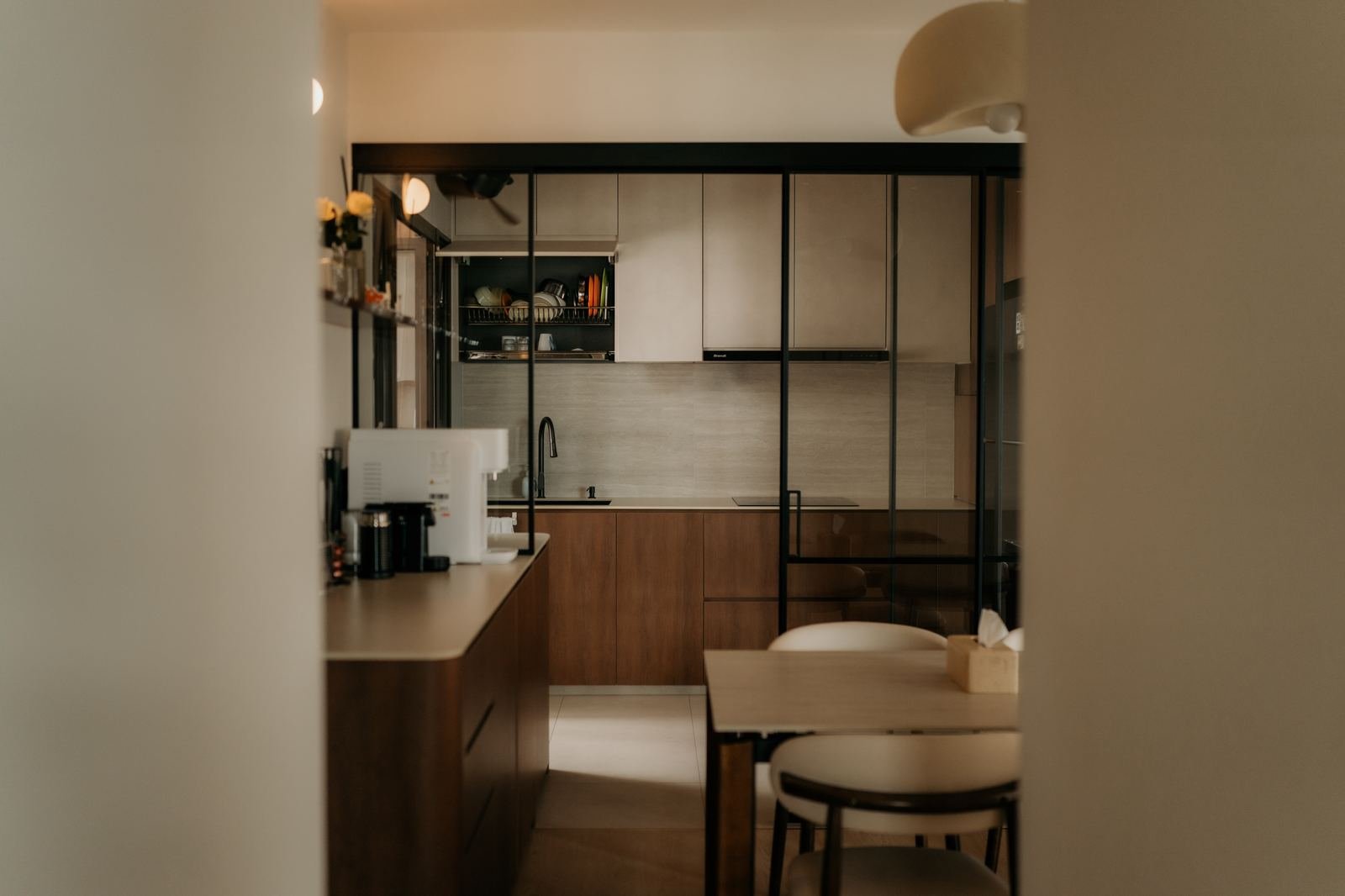 Kitchen viewed through black-framed glass partition